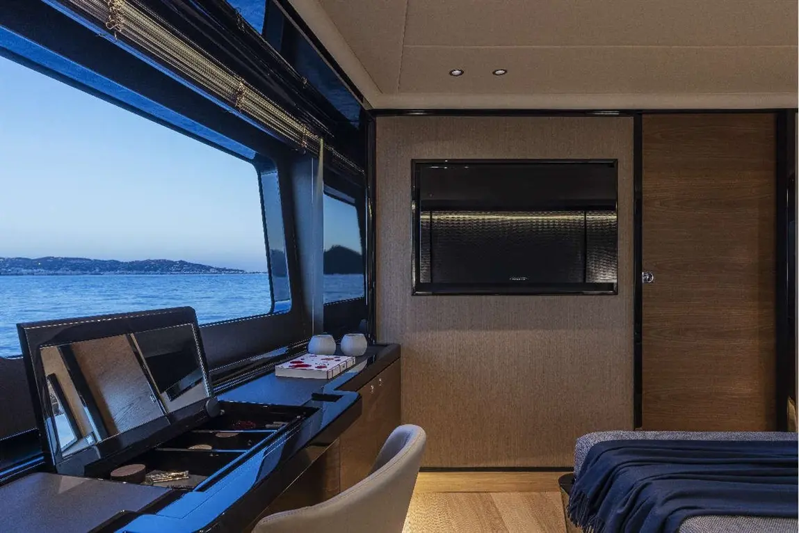Modern yacht interior featuring large windows with sea views, a TV, and a stylish vanity with mirror and storage.